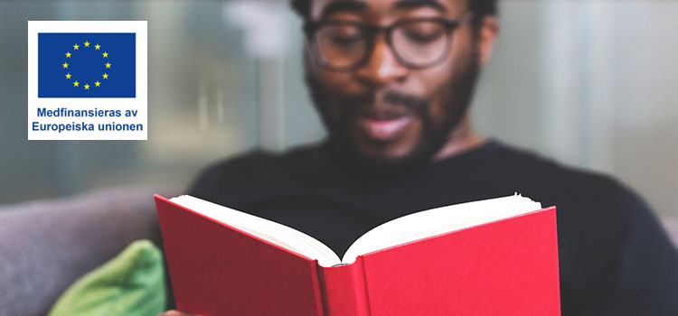 Man i glasögon läser i en röd bok
