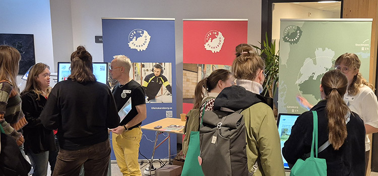 Personer vid Livet i Skaraborgs monter på mässa