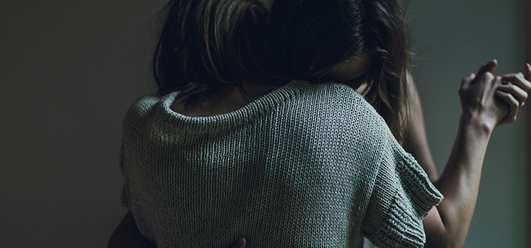 Två personer kramar varandra i ett mörkt rum