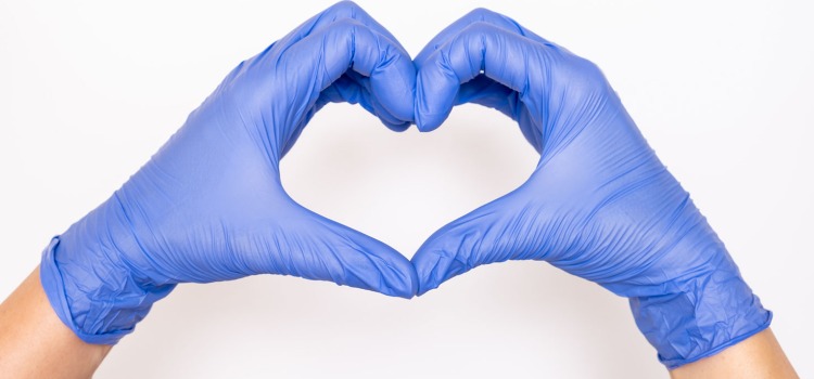 Händer i blåa handskar formas som ett hjärta