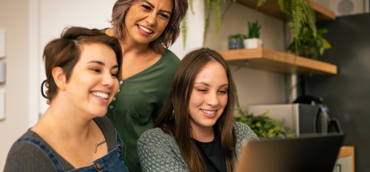 Tre glada kvinnor vid en dator 